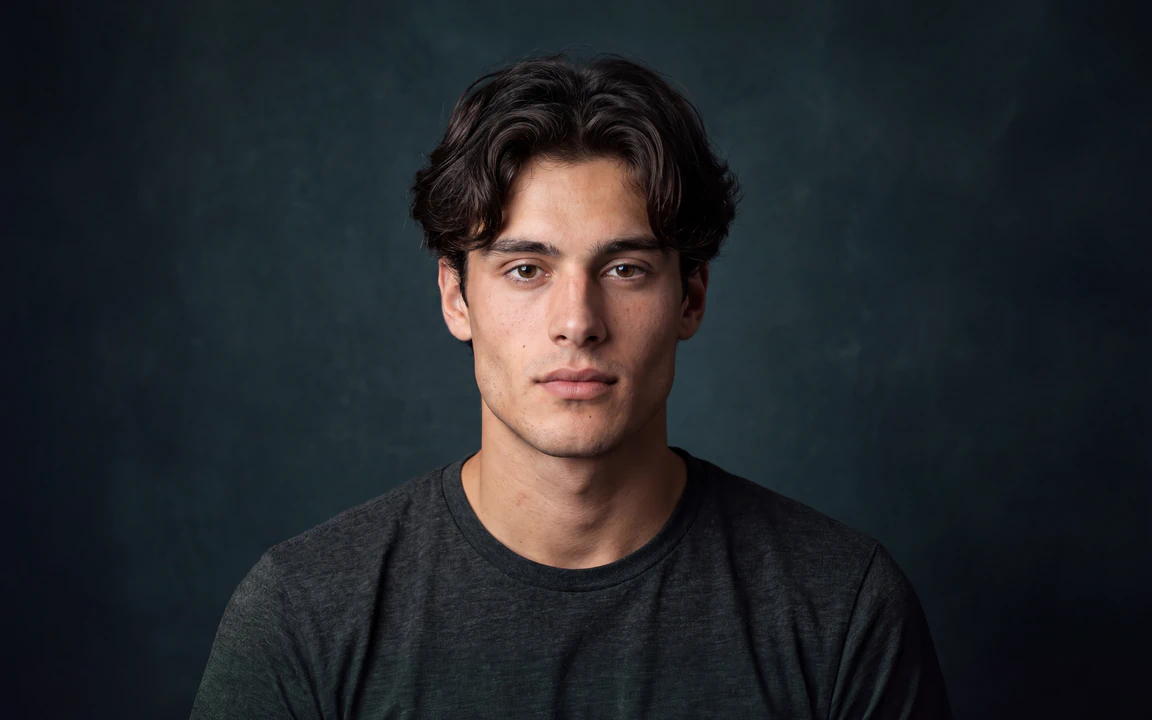 Studio headshot of a young man in a charcoal tee, facing the camera